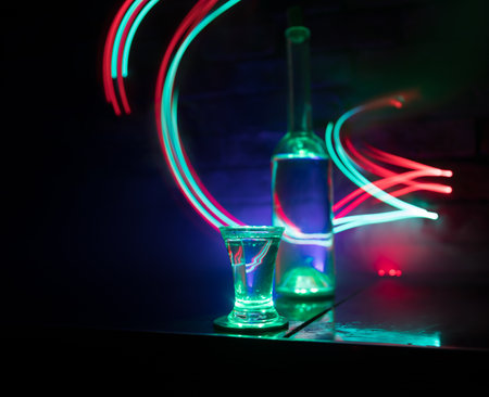 Cold vodka glass on a dark background in the neon light or glasses of russian vodka on bar background. selective focusの写真素材