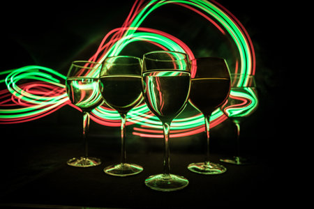 Wine glass on dark bar background low light. Colorful wine glasses with light on backside in selective focusの写真素材