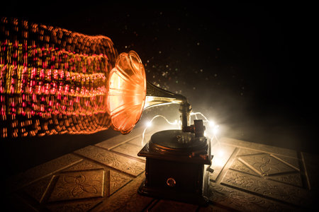 music concept. Old gramophone on a dark background. Retro gramophone with disc on wooden table with toned backlight. selective focusの写真素材