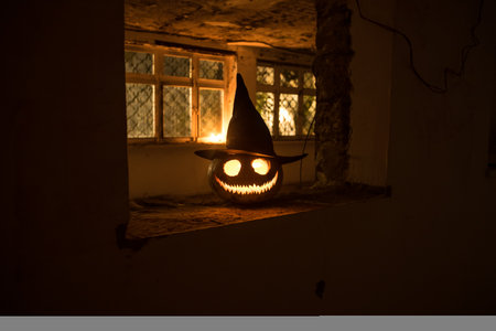Scary Halloween pumpkin in the mystical house window at night or halloween pumpkin in night on abandoned room with window. selective focusの写真素材