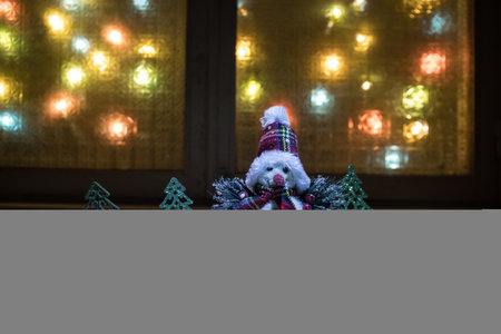 Christmas and New year concept.Fir tree standing on snow with beautiful holiday decorated background and traditional holiday attributes. Cozy window with colorful lights on background. selective focusの写真素材