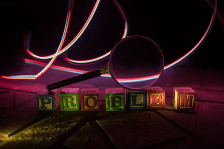 Loupe analyzing the word "problem" on wooden cubes in dark backgroung. Selective focusの写真素材