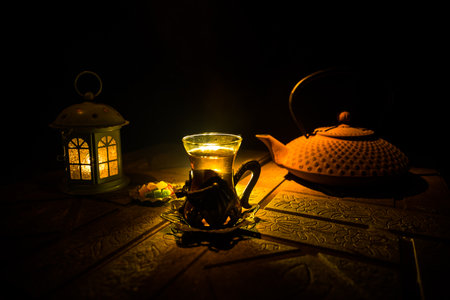 Arabian tea in glass with eastern snacks on a stone surface on dark background with lights and smoke. Eastern tea concept. selective focus.の写真素材
