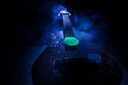 music concept. Acoustic guitar isolated on a dark background under beam of light with smoke with copy space. Guitar Strings, close up. selective focus.の写真素材