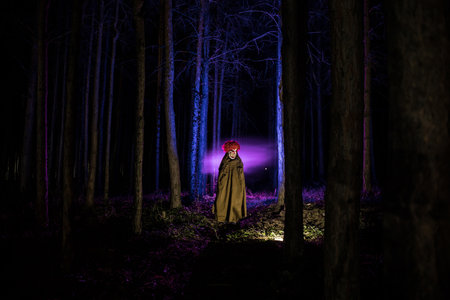 a scary evil clown wearing a dirty costume in the woods at night. Night forest, horror Halloween conceptの写真素材
