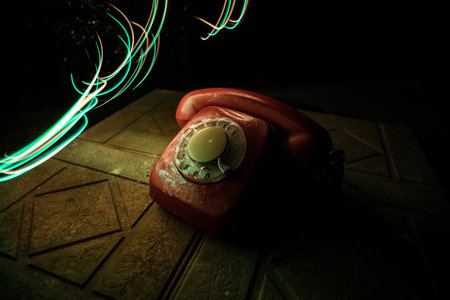 old red telephone on grunge stone surface with art dark background with fog and toned light. empty space. selective focusの写真素材