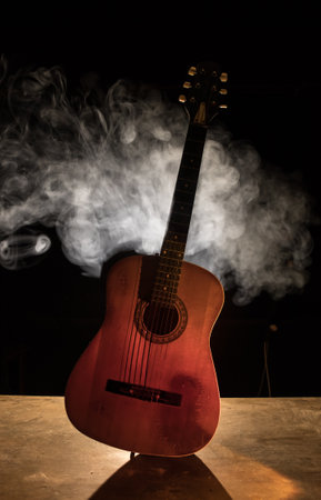music concept. Acoustic guitar isolated on a dark background under beam of light with smoke with copy space. Guitar Strings, close up. selective focus.の写真素材