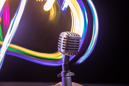 Microphone for sound, music, karaoke in audio studio or stage. Mic technology. Speech broadcast equipment. Microphone in dark room on table with backlight. selective focusの写真素材