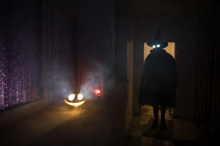 Halloween concept. Creepy silhouette in the dark corridor with pumpkin head. Toned light with fog on background. selective focus. long shutter shotの写真素材