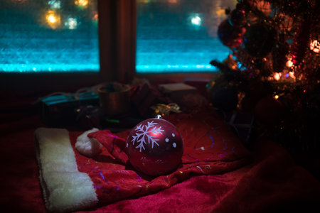 Christmas and New year concept.Fir tree standing on red carpet with traditional holiday attributes. Cozy window with colorful lights on background. selective focusの写真素材
