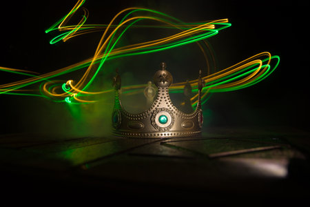 low key image of beautiful kings crown over wooden table. vintage filtered. fantasy medieval period. selective focus. colorful backlightの写真素材