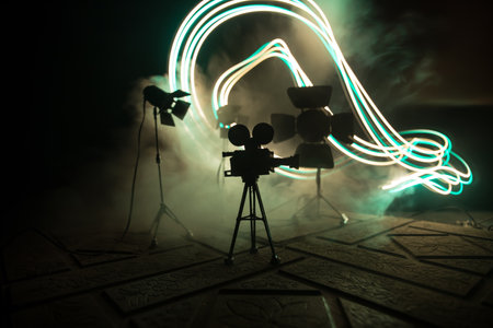 movie concept. Miniature movie set on dark toned background with fog and empty space. Silhouette of vintage camera on tripod. selective focusの写真素材