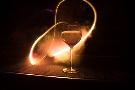 Wine glass on dark bar background low light. Colorful wine glasses with light on backside in selective focusの写真素材