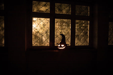 Scary Halloween pumpkin in the mystical house window at night or halloween pumpkin in night on abandoned room with window. selective focusの写真素材