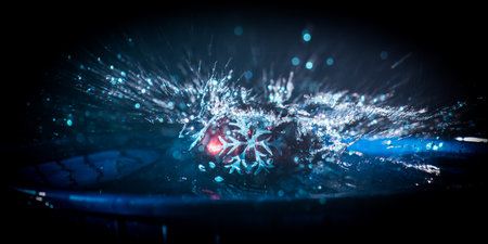 New year and Christmas concept. Glass bauble dropped into water or water splash on dark foggy background. selective focus.の写真素材