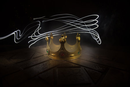 low key image of beautiful kings crown over wooden table. vintage filtered. fantasy medieval period. selective focus. colorful backlightの写真素材