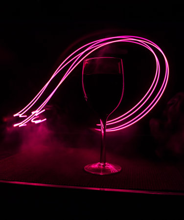 Wine glass on dark bar background low light. Colorful wine glasses with light on backside in selective focusの写真素材