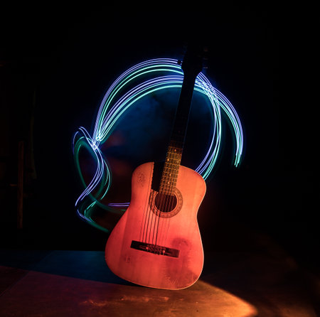 music concept. Acoustic guitar isolated on a dark background under beam of light with smoke with copy space. Guitar Strings, close up. selective focus.の写真素材