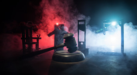 Legal law or crime and execution concept. Death penalty miniatures on table. Man alone looking to execute at night. Artwork decoration with handcuffs, Statue of Justice and mallet of justiceの写真素材