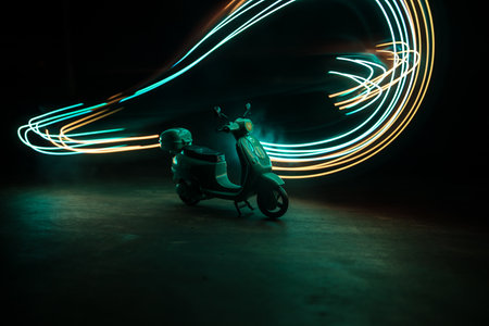 Silhouette of scooter miniature standing on dark background with light. selective focusの写真素材