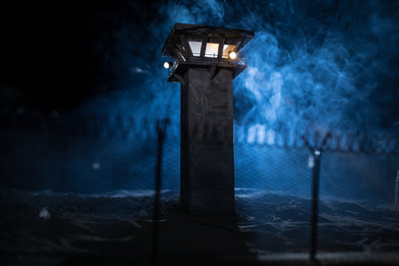 Criminal justice imprisonment concept. Old prison watchtower protected by wire of prison fence at...