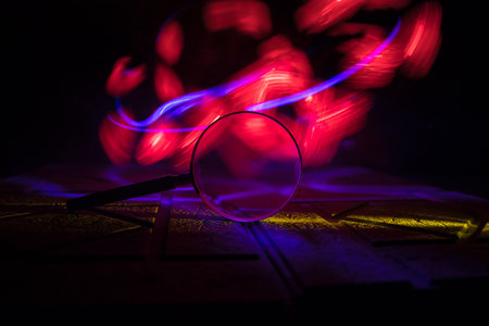 Magnifying glass on stone surface in dark background, under the light, mysterious detective conceptの写真素材