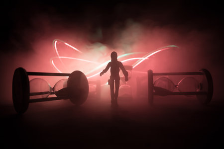 Time concept. Silhouette of a man standing between hourglasses with smoke and lights on a dark background. Surreal decorated pictureの写真素材