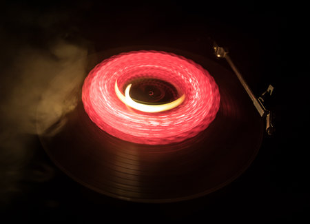 Music DJ concept. Trail of fire and smoke on vinyl record. Burning vinyl disk. Turntable vinyl record player on dark background. selective focusの写真素材