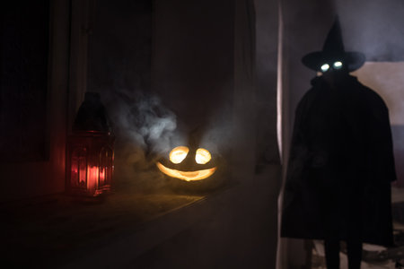 Halloween concept. Creepy silhouette in the dark corridor with pumpkin head. Toned light with fog on background. Selective focus. Long shutter shotの写真素材