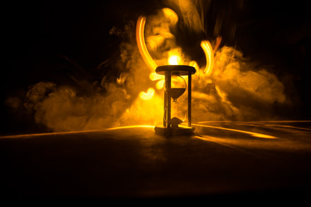 Hourglass as time passing concept for business deadline, urgency and running out of time. Sandglass, egg timer on dark background showing the last second or last minute or time out. With copy space.の写真素材