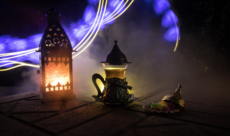Arabian tea in glass with eastern snacks on a stone surface on dark background with lights and smoke. Eastern tea concept. selective focus.の写真素材