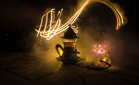 Arabian tea in glass with eastern snacks on a stone surface on dark background with lights and...