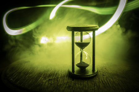 Hourglass as time passing concept for business deadline, urgency and running out of time. Sandglass, egg timer on dark background showing the last second or last minute or time out. With copy space.の写真素材
