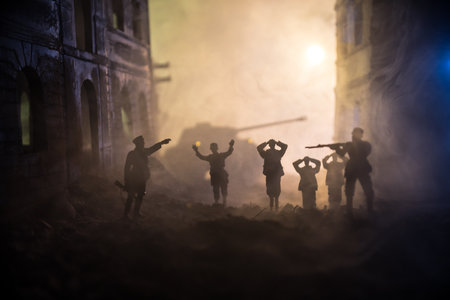 Military silhouettes fighting scene on war fog sky background. A German soldiers raised arms to surrender. Plastic toy soldiers with guns taking prisoner the enemy soldier. Selective focusの写真素材