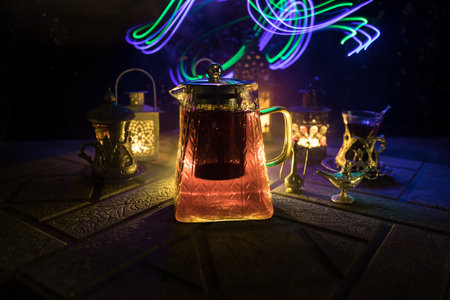 Arabian tea in glass with eastern snacks on a stone surface on dark background with lights and smoke. Eastern tea concept. selective focus.の写真素材