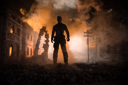 Artwork decoration. A man standing on a road of burnt up city. Apocalyptic view of city downtown as disaster film poster concept. Night scene. City destroyed by war. Selective focusの写真素材