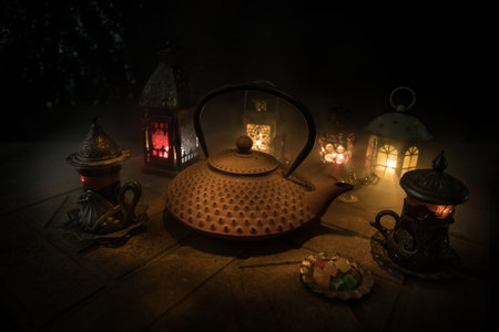 Arabian tea in glass with eastern snacks on a stone surface on dark background with lights and smoke. Eastern tea concept. selective focus.の写真素材