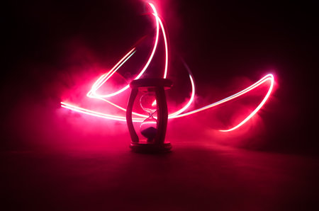 Hourglass as time passing concept for business deadline, urgency and running out of time. Sandglass, egg timer on dark background showing the last second or last minute or time out. With copy space.の写真素材