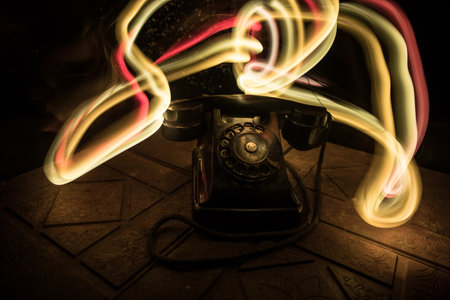 old black telephone on old wood plank with art dark background with fog and toned light. empty...