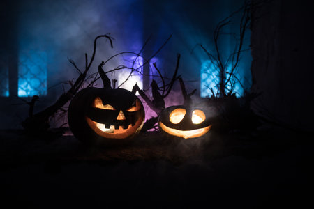 Scary Halloween pumpkin in the mystical house window at night or halloween pumpkin in night on abandoned room with window. selective focusの写真素材
