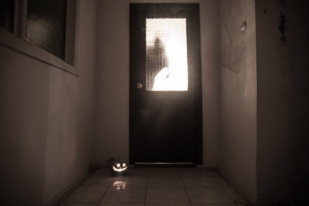 Halloween concept. Creepy silhouette in the dark corridor with pumpkin head. Toned light with fog on...