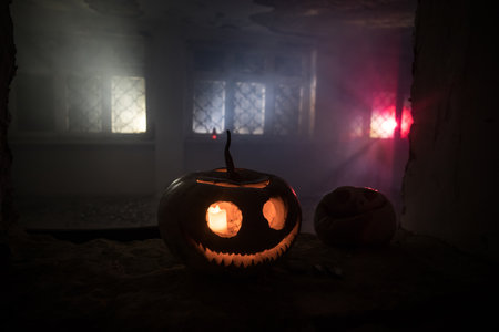 Scary Halloween pumpkin in the mystical house window at night or halloween pumpkin in night on abandoned room with window. selective focusの写真素材