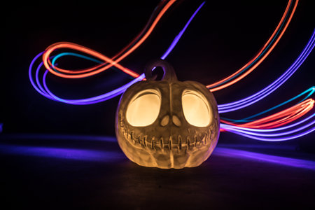Halloween concept. Halloween pumpkin head in dark on table. Toned light with fog on background. Selective focus. Long shutter shotの写真素材