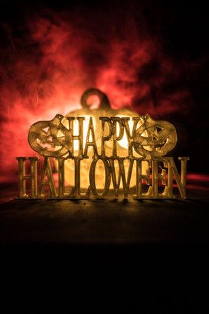 Halloween concept. Halloween pumpkin head in dark on table. Toned light with fog on background. Selective focus. Long shutter shotの写真素材