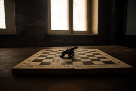 Medieval battle scene with cannon on chessboard. Chess board game concept of business ideas and competition and strategy ideas Chess figures on a dark background with smoke and fog.の写真素材