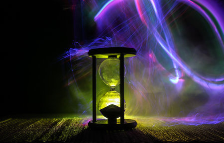 Hourglass as time passing concept for business deadline, urgency and running out of time. Sandglass, egg timer on dark background showing the last second or last minute or time out. With copy space.の写真素材