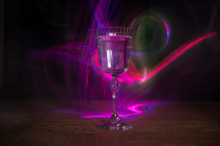 Wine glass on dark bar background low light. Colorful wine glasses with light on backside in selective focusの写真素材