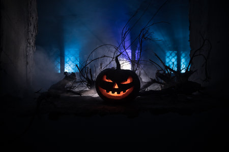 Scary Halloween pumpkin in the mystical house window at night or halloween pumpkin in night on abandoned room with window. selective focusの写真素材