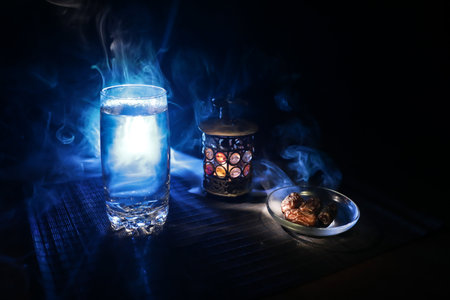 Suhoor or iftar time during Ramadan fasting. A glass of water and dates to break the fast. Festive greeting card, invitation for Muslim holy month of Ramadan. Selective focusの写真素材