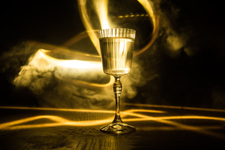 Wine glass on dark bar background low light. Colorful wine glasses with light on backside in...